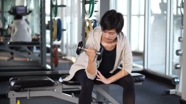 Deportivo fresco asiático mujer entrenamiento dumbbell lifting en gimnasio — Vídeos de Stock