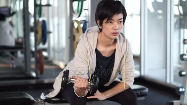 Deportivo fresco asiático mujer entrenamiento dumbbell lifting en gimnasio — Vídeos de Stock