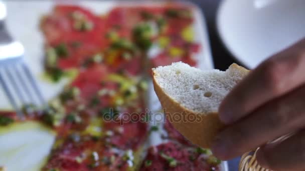 Biff carpaccio förrätt maträtt. hand att sätta skivad rå nötkött på bröd — Stockvideo