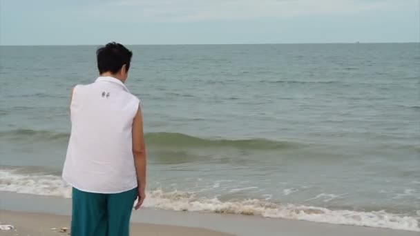 Asiática senior mujer caminando solo a lo largo de la playa disfrutando de la naturaleza — Vídeos de Stock