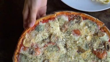 Ev yapımı pizza dilimi plaka üzerinde ahşap masa alarak eller