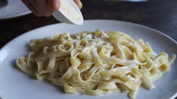 Добавление сыра в спагетти из карбонары и смешивание с вилкой — стоковое видео