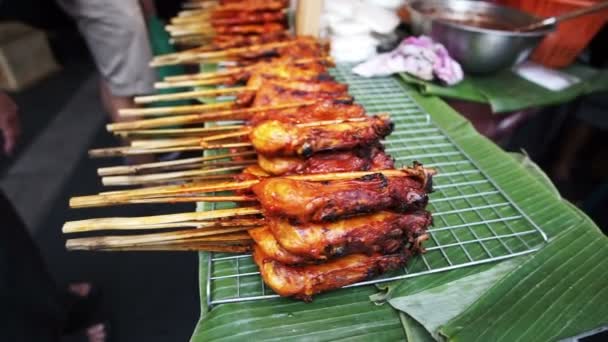 Brochetas tradicionales tailandesas de pollo a la parrilla. Montón de comida callejera tailandesa deliciosa barata que vende en el vendedor de hojas de plátano — Vídeo de stock