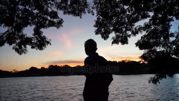 Silueta de hombre mayor asiática al amanecer bajo sombra de árbol. Pensando en la vida — Vídeo de stock