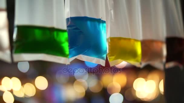 Colorful water in plastic bag hanging as night festival decoration. Bokeh light background — Stock Video