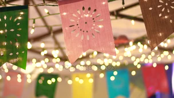 Slow motion shot of Colorful festival flags at night with garland light bokeh decoration — Stock Video