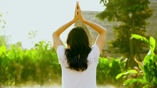 Asian girl exercise yoga next to wellness spa pool in the sun with green background and morning fog slow motion shot — Stock Video