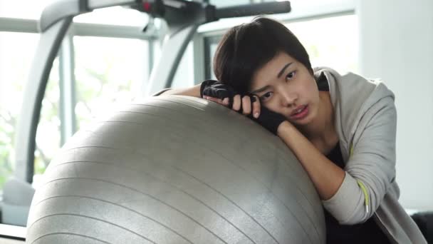 Cheveux courts fille asiatique à la salle de gym avec balle de yoga tir. Fatigué épuisé mais toujours sourire — Video