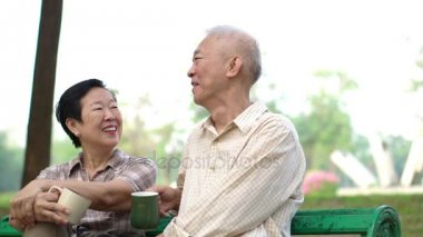 Ağır çekim Asya emekli çift konuşmak ve sabah park açık kahve içme