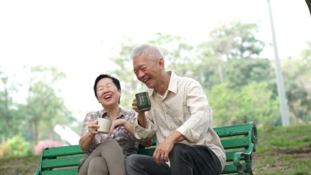 Slow motion asiatique retraité couple parler et boire du café le matin parc extérieur — Video