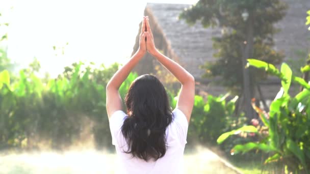 Slow motion Asian woman doing morning yoga next to swimming pool and green surrounding — Stock Video