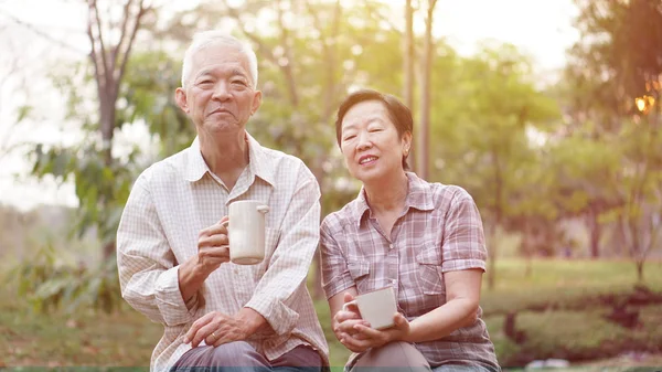 Casual Asian couple citizen drinking tea in mornign garden light — Stock Photo, Image