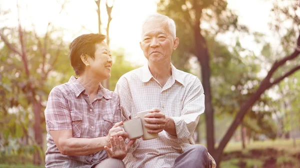 Saudável asiático casal sênior beber café no parque da manhã toge — Fotografia de Stock