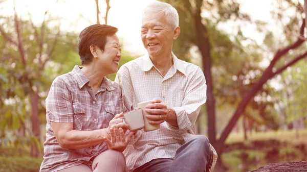 Здоровая азиатская старшая пара пьет кофе в утреннем парке — стоковое фото