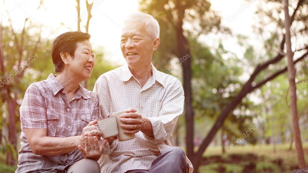 Healthy Asian senior couple drinking coffee in morning park toge