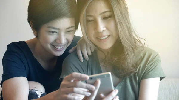 Duas mulheres asiáticas verificando foto selfie no telefone inteligente juntos , — Fotografia de Stock