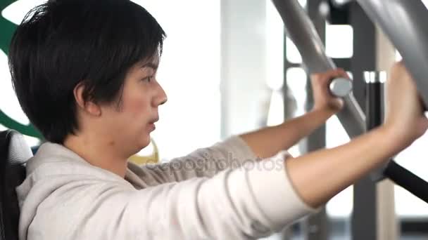 Asian adult female athlete exercising in fitness gym doing machine weight lifting — Stock Video