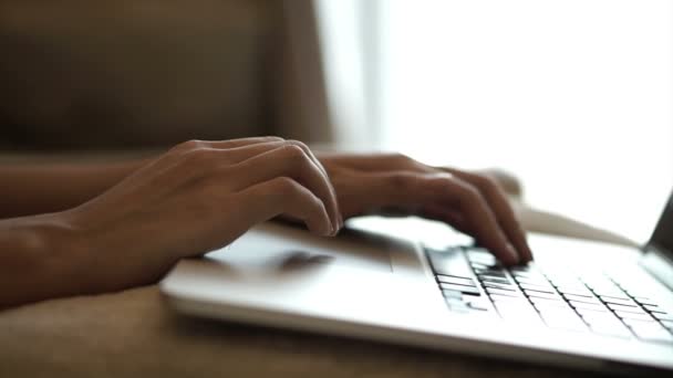 Acercamiento de una joven freelancer manos escribiendo en un teclado portátil en casa — Vídeos de Stock