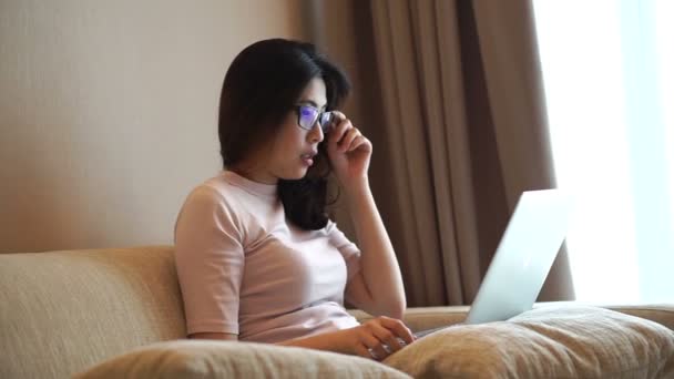 ラップトップ コンピューターの良いニュースから幸せの反応と一緒に家で働くアジアの女性 — ストック動画