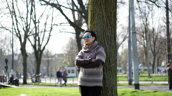 Asian senior woman travel in europe taking portrait in park — Stock Photo, Image