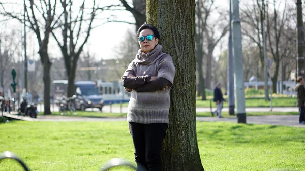 Asian senior woman travel in europe taking portrait in park — Stock Photo, Image