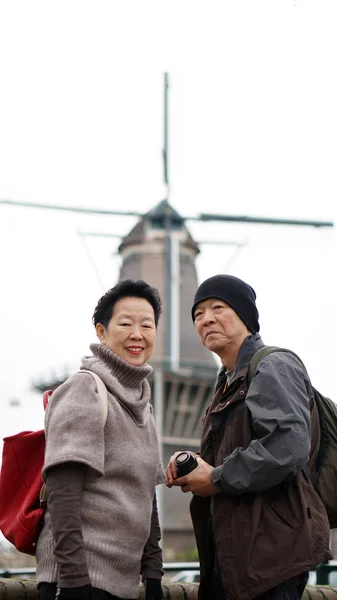 Asiatiska senior par årsdagen resa för att se Nederländerna väderkvarn — Stockfoto