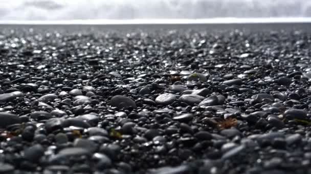 4K Black sandy lava beach in Vik, Iceland. Low angle, tilt up landmark beach near basalt sea stacks — Stock Video