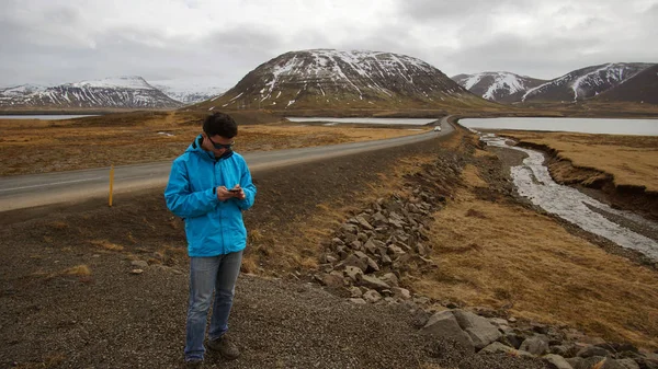 Азиатский мужчина, использующий смартфон для интернет GPS для дорожной поездки и социальных медиа во время путешествия в Исландию — стоковое фото