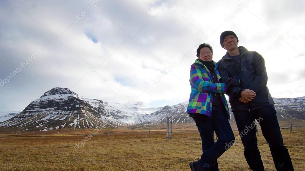 Asian senior couple enjoy anniversary trip in Europe. Iceland volcanic landscape mountain with snow amazing view