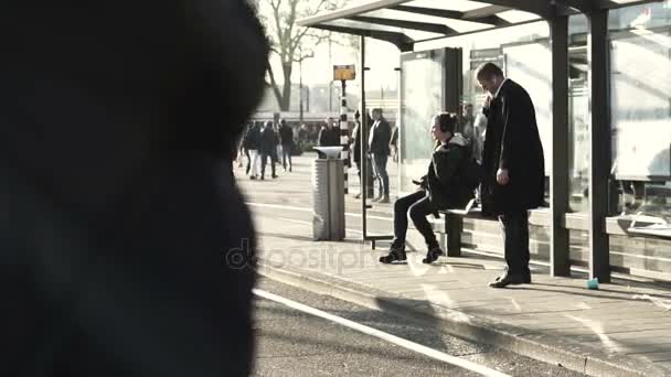 Amsterdam, Nederländerna - April 2017: Vacker morgon solljus och personer på centralstation väntar på spårvagnen transport. Slow motion 120fps — Stockvideo