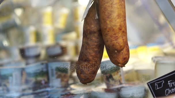 Dried sausage hanging in market freezer with cheese and other product — Stock Video