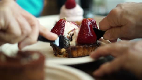 Manos y tenedores comiendo, cortando, compartiendo tarta de fresa juntos — Vídeos de Stock