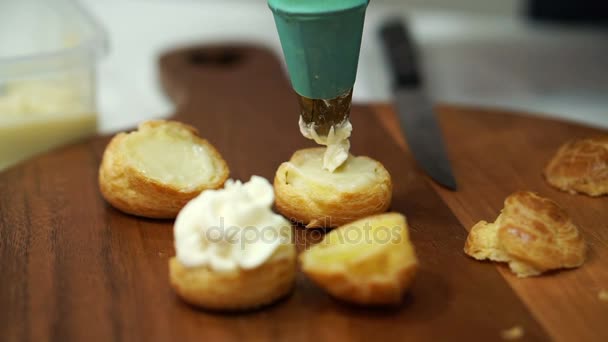 Mano che fa il soffio di crema di chuox di riempimento e che organizza per la vendita in panetteria — Video Stock