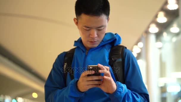 Τόκιο, Ιαπωνία - Δεκεμβρίου 2017: Ασίας backpacker άνθρωπος τον έλεγχο χρησιμοποιώντας έξυπνο τηλέφωνο στο αεροδρόμιο — Αρχείο Βίντεο