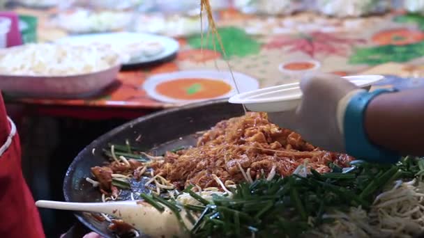 Pad thai vente au marché de nuit mettant dans l'assiette pour le touriste à Bangkok — Video