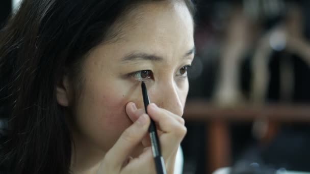 Ασιατικές γυναίκα κάνει make up, αντλώντας eyeliner μπροστά από καθρέφτη αργή κίνηση. Ομορφιά και αισθητική αντίληψη — Αρχείο Βίντεο