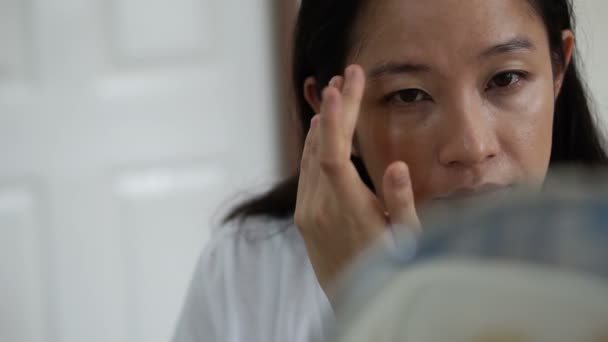 Asiatin trägt Foundation auf ihr Gesicht auf, bevor sie sich in Zeitlupe kosmetisch schminkt — Stockvideo