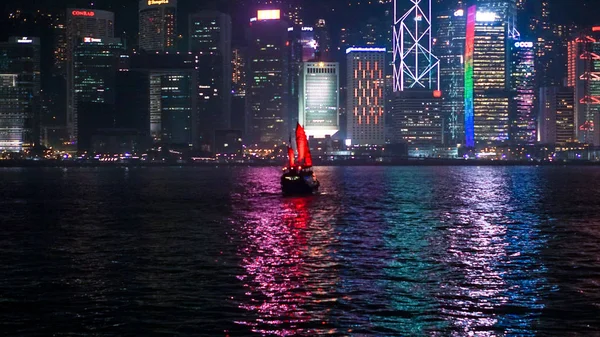 Hong Kong iconic red vintage sail boat sailing at night skyline background — Stock Photo, Image