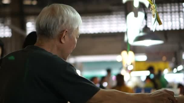 Asian senior man buying food at local market stall — Stock Video