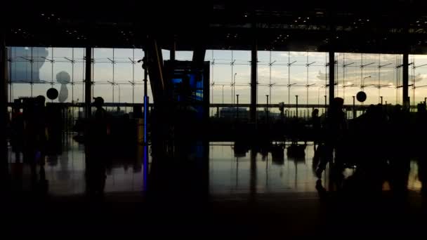 Multitud de personas silueta caminando contraste con la arquitectura de vidrio de luz del sol de la mañana en el aeropuerto — Vídeos de Stock