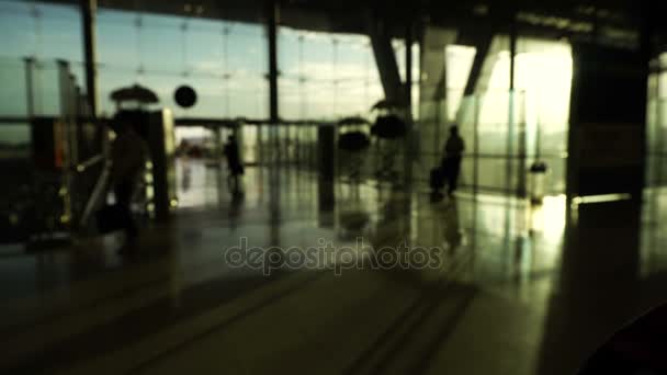 Blur tömeg az emberek sziluettje, gyaloglás üveg szerkezet és a napkelte háttérrel repülőtéren. Absztrakt üzleti és utazó