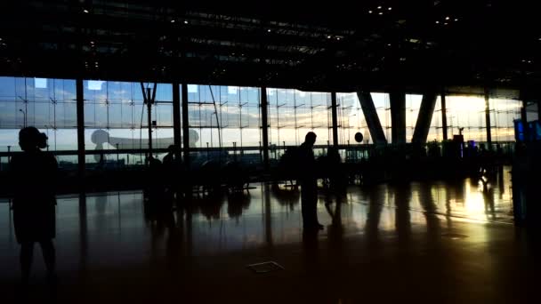 空港で朝太陽光ガラス建築とのコントラストを歩く人々 のシルエットの群れ — ストック動画