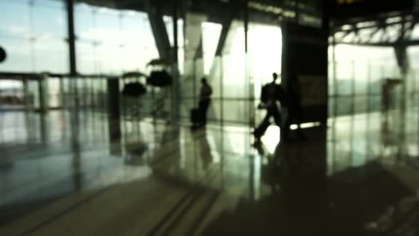 Menigte van mensen silhouet wandelen in luchthaven met glazen structuur en zonsopgang achtergrond vervagen. Abstracte zaken en reiziger — Stockvideo