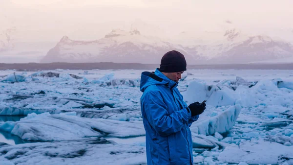 アジア男手配、氷河ラグーン アイスランドでスマート フォンを使用します。世界旅行先 — ストック写真