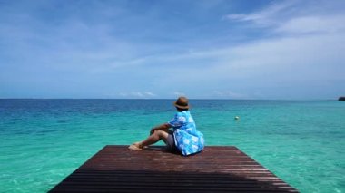 Ahşap güverte oturan kişi huzurlu ve sakin bir deniz ve güzel gökyüzü sakin ol