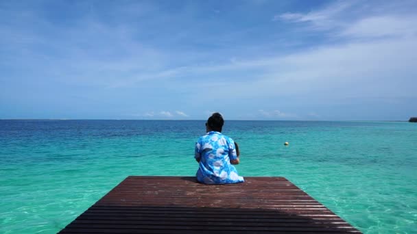 Pessoa sentada no convés de madeira relaxar no mar tranquilo e calmo e céu agradável — Vídeo de Stock