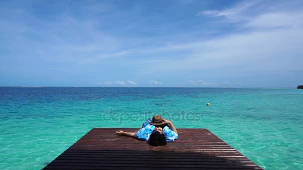 女人放松地回头望着木头甲板上的绿松石天堂般的海岛 — 图库视频影像