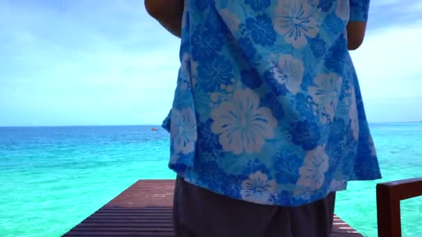 Женщина расслабляется, глядя на бирюзовый рай острова океан на деревянной палубе — стоковое видео