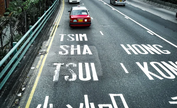 Tsim Sha Tsui, Hong Kong letreros de letras blancas en la carretera de carretera con taxi clásico rojo —  Fotos de Stock