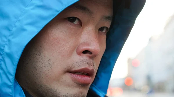 Nahaufnahme eines asiatischen Mannes mit blauer Kapuzenjacke — Stockfoto